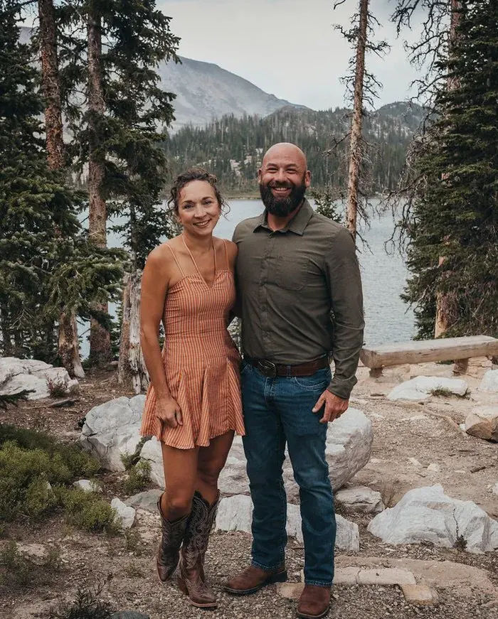 Adam and Bekah Marshall standing together beside a mountain lake